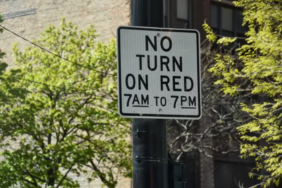 "No right turn on red 7am to 7pm" sign on black post